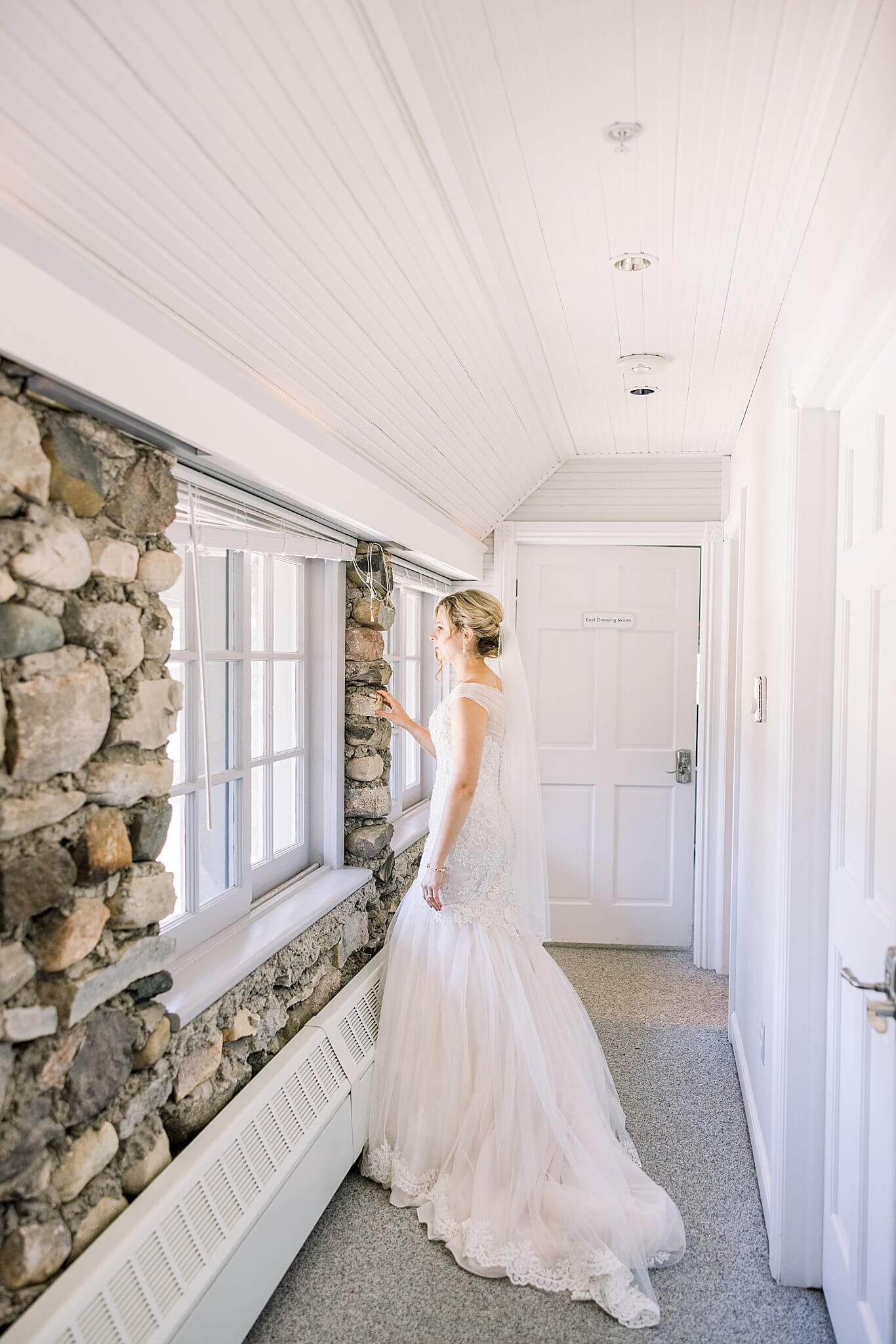 Bride looks through Castle Farms window overlooking her ceremony space in the Queen's Courtyard.