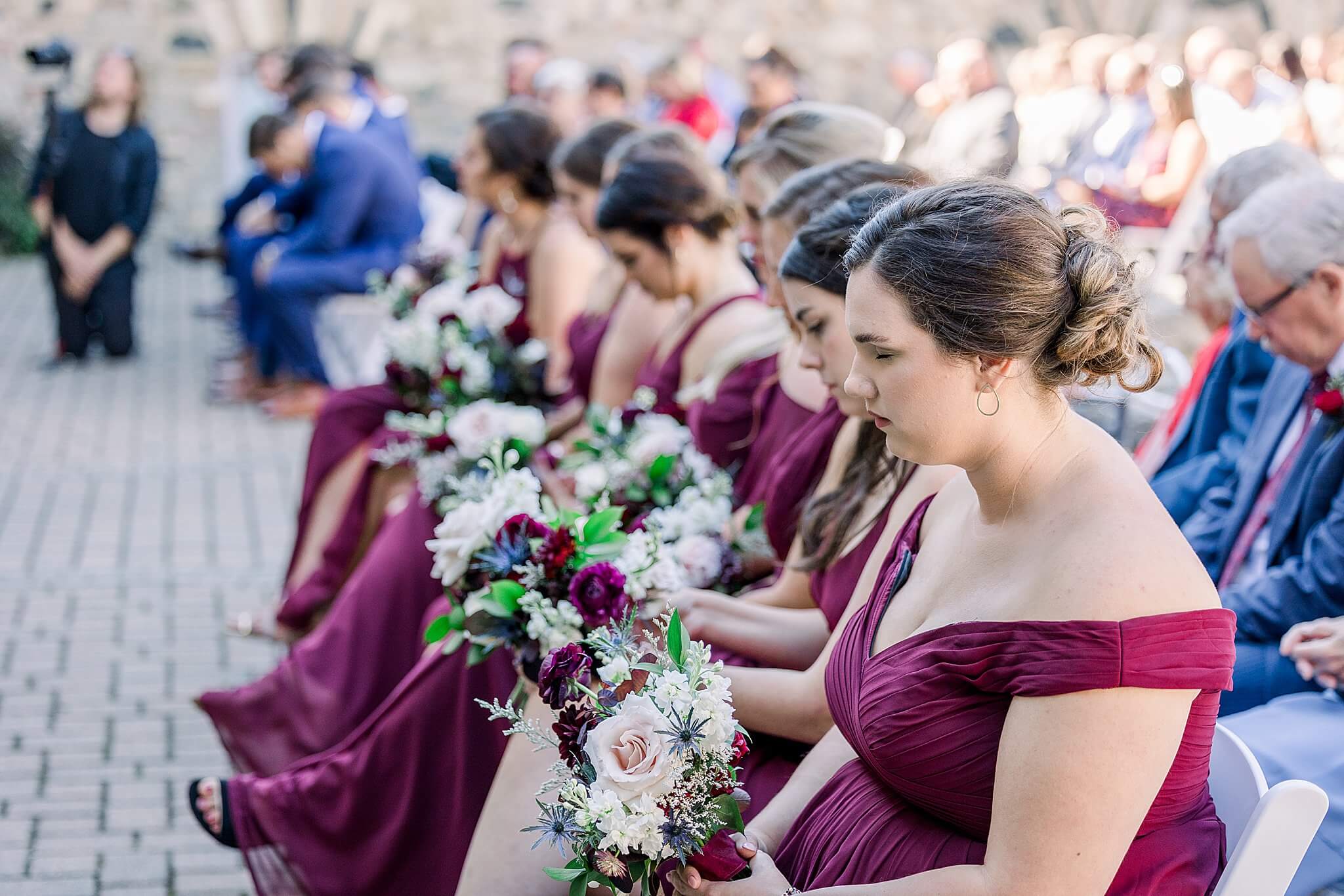 Bridesmaids bow their heads during prayer at wedding ceremony at Castle Farms.