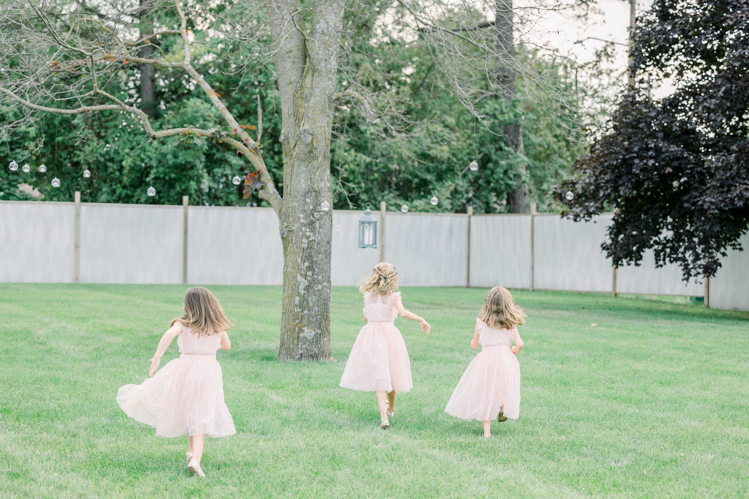 Flower girls run on lawn at The Boathouse on Lake Charlevoix in East Jordan, Michigan.