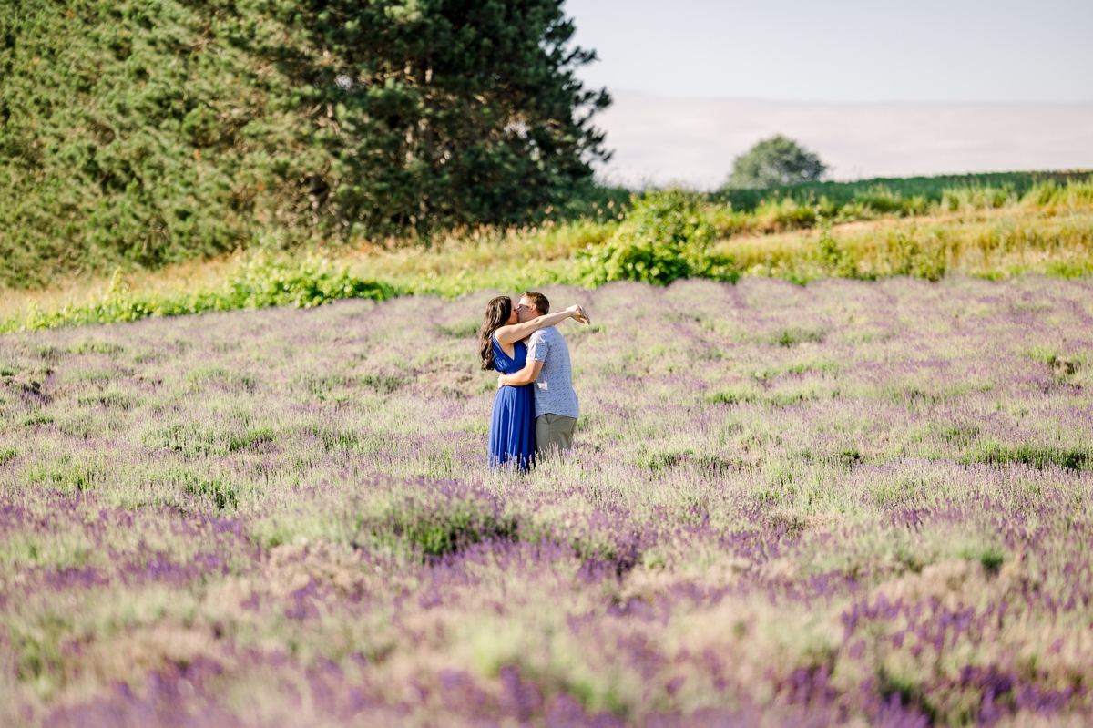 Lindsey and Austin hugging and kissing off in the distance in the middle of a lavender field.