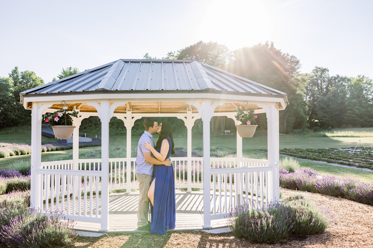 Austin and Lindsey kissing under a gazebo at the lavender field during their engagement session with Mandie Forbes Photography.