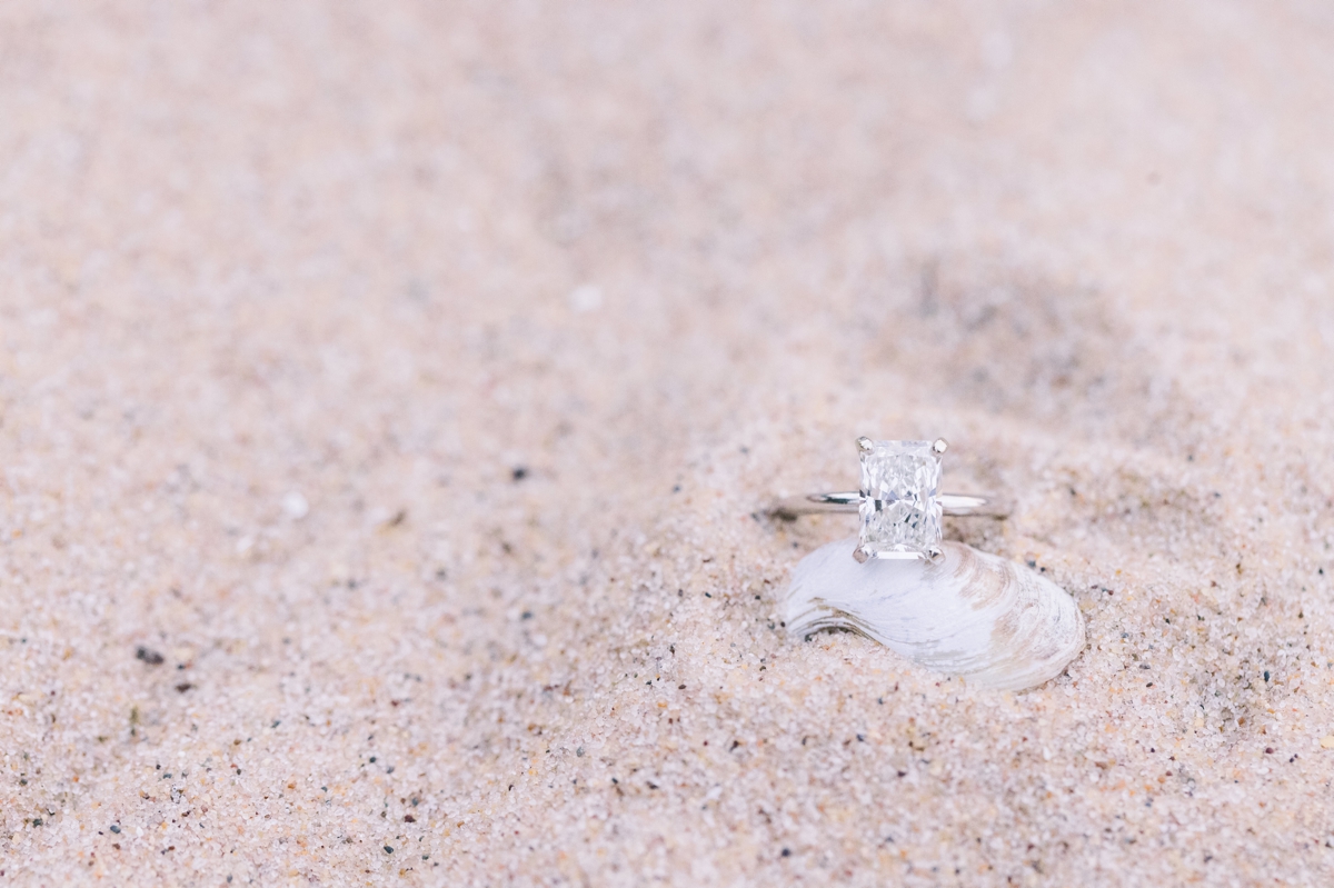 Marissa's elongated cushion cut diamond engagement ring in the sand.