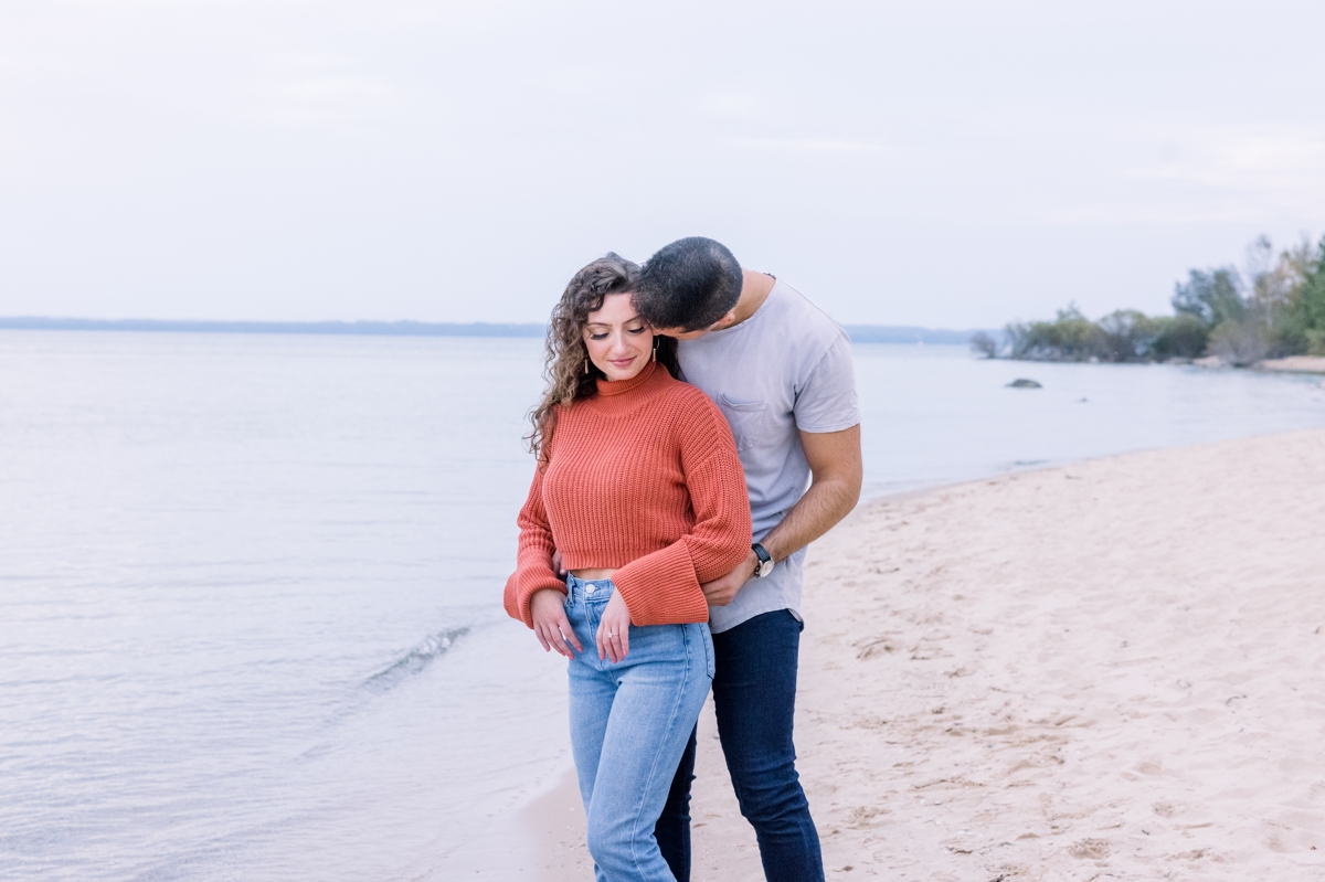 Alex hugging Marissa from behind while he kisses her shoulder during their engagement session with Mandie Forbes Photography.