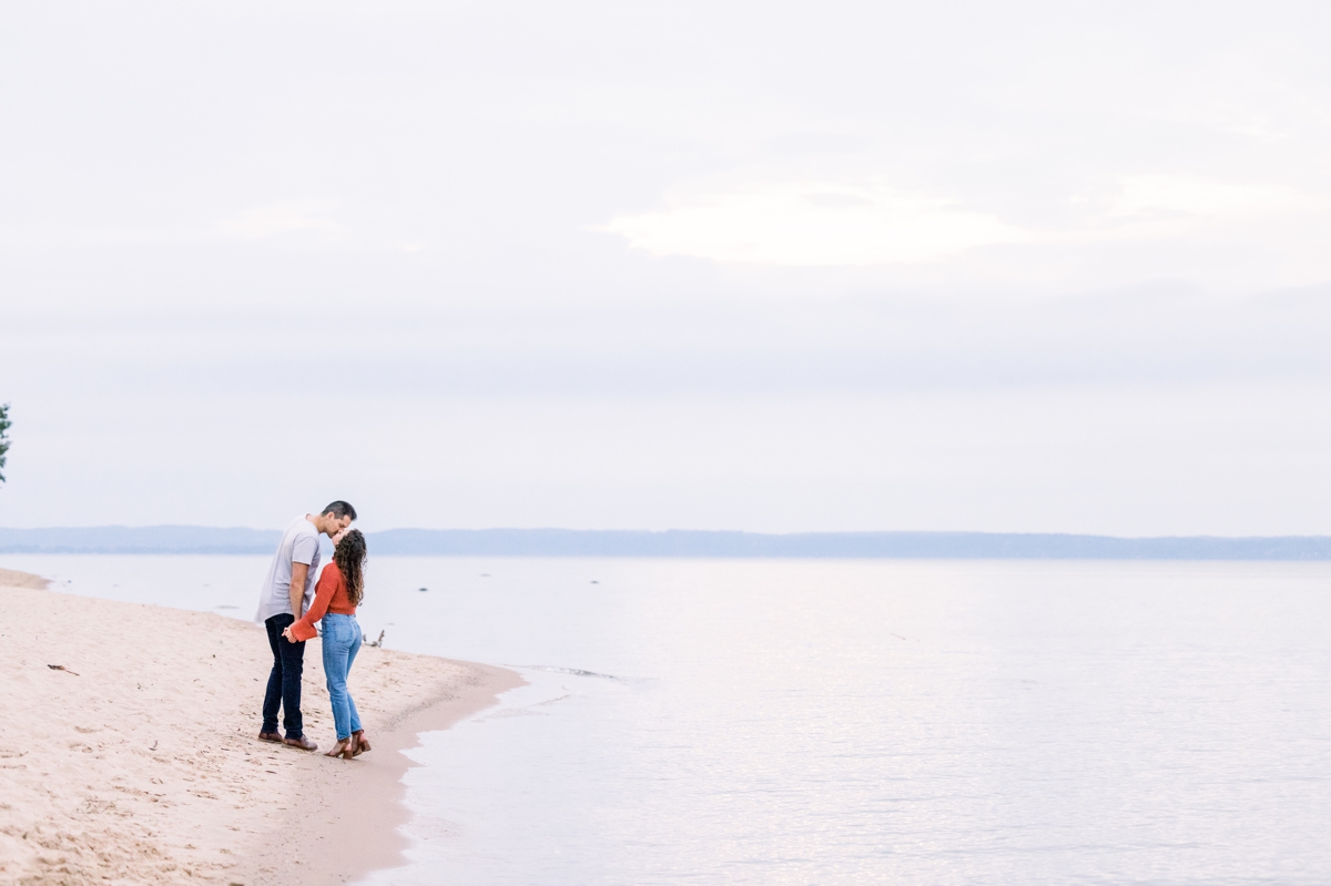 Marissa and Alex kissing on the ocean's edge during their beach engagement session.
