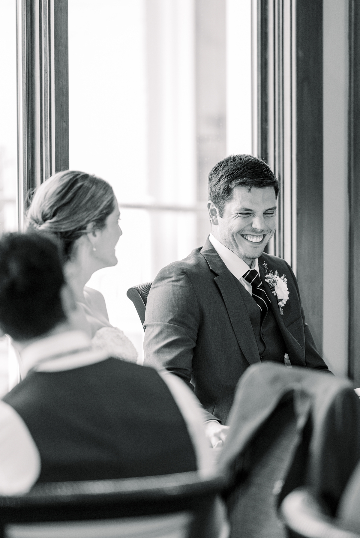 Black and white photo of the groom laughing during his best man's speech at the Perry Hotel.
