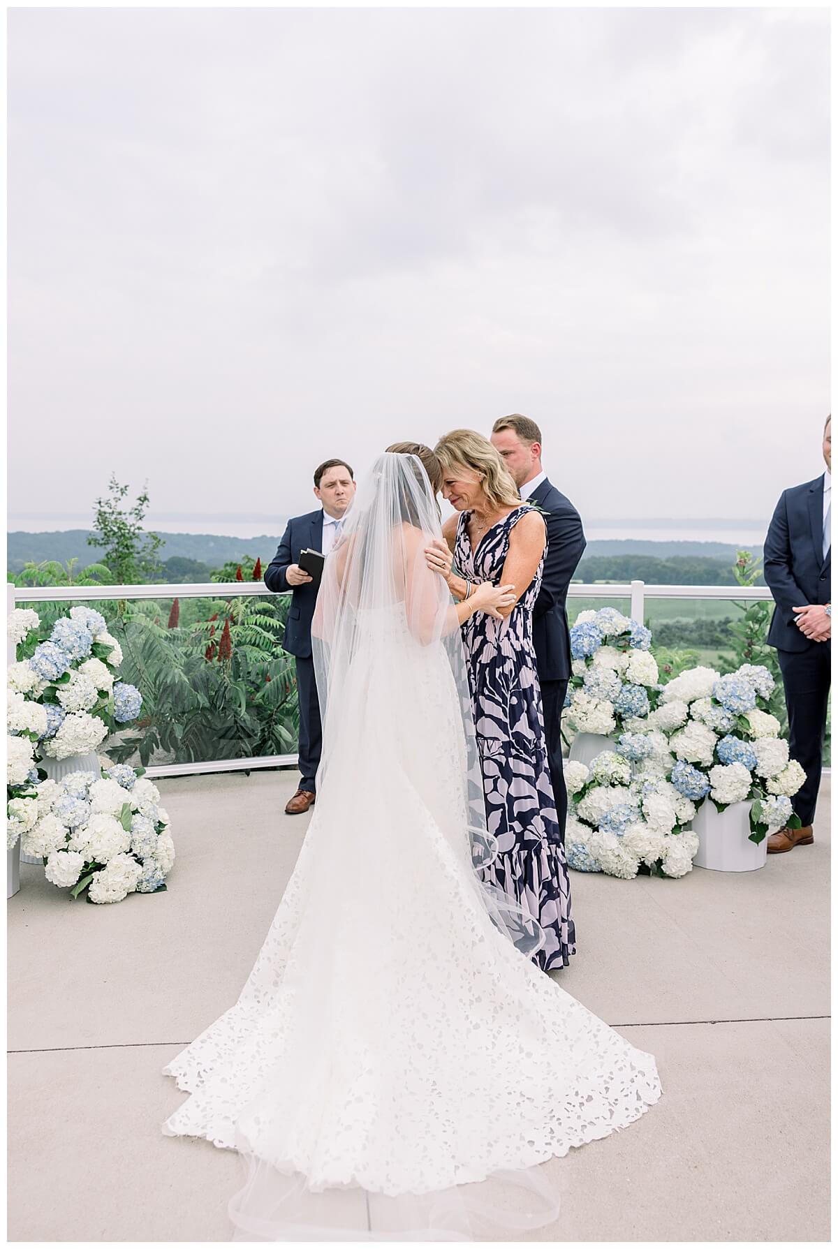 A bride and her mom share an emotional moment at the end of the aisle before mom hands bride off to the groom during emotional Bay View wedding day ceremony.
