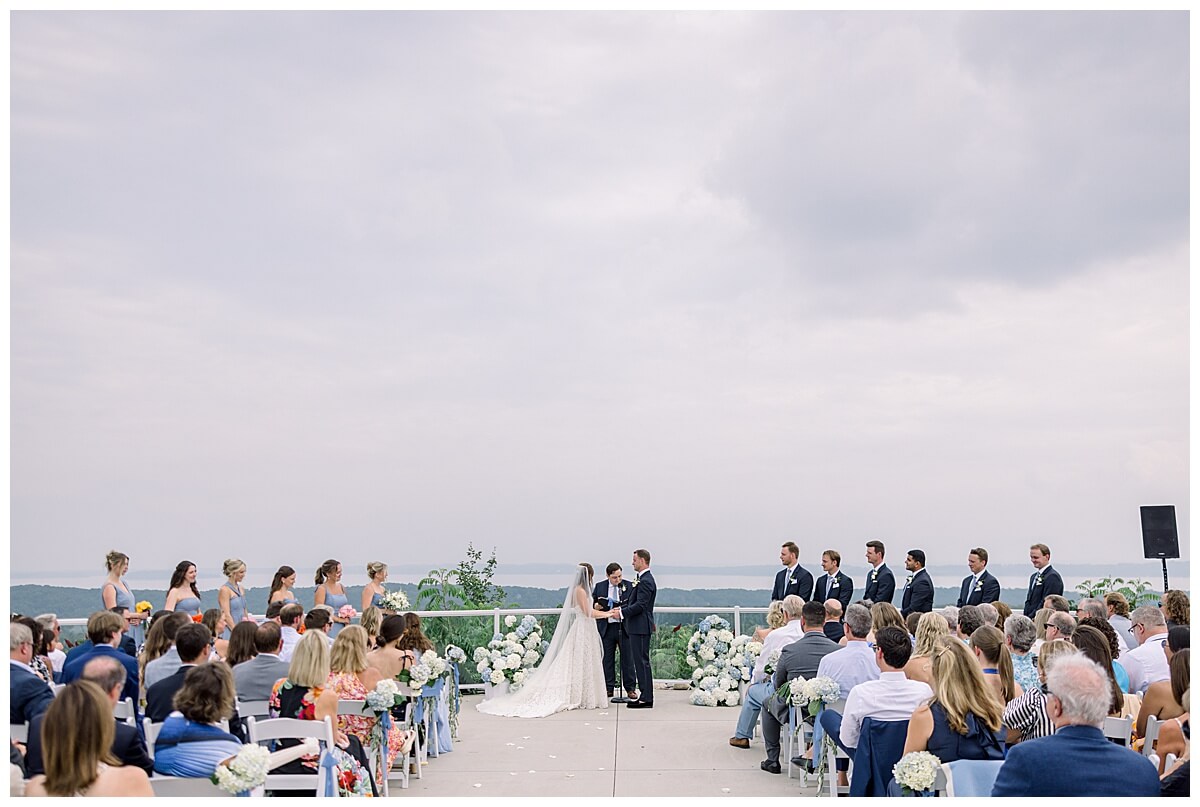 A beautiful cloudy wedding ceremony at Bay View Weddings at Gallagher Farms located on their hilltop ceremony site that overlooks the Grand Traverse Bay in the distance.