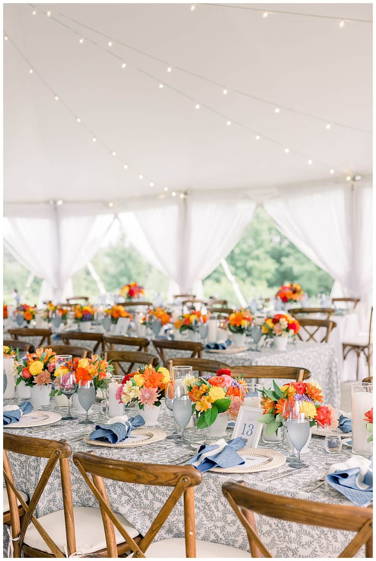 Northern Michigan sunset inspired florals decorate a luxury wedding tent at Bay View Weddings by Gallagher Farms.