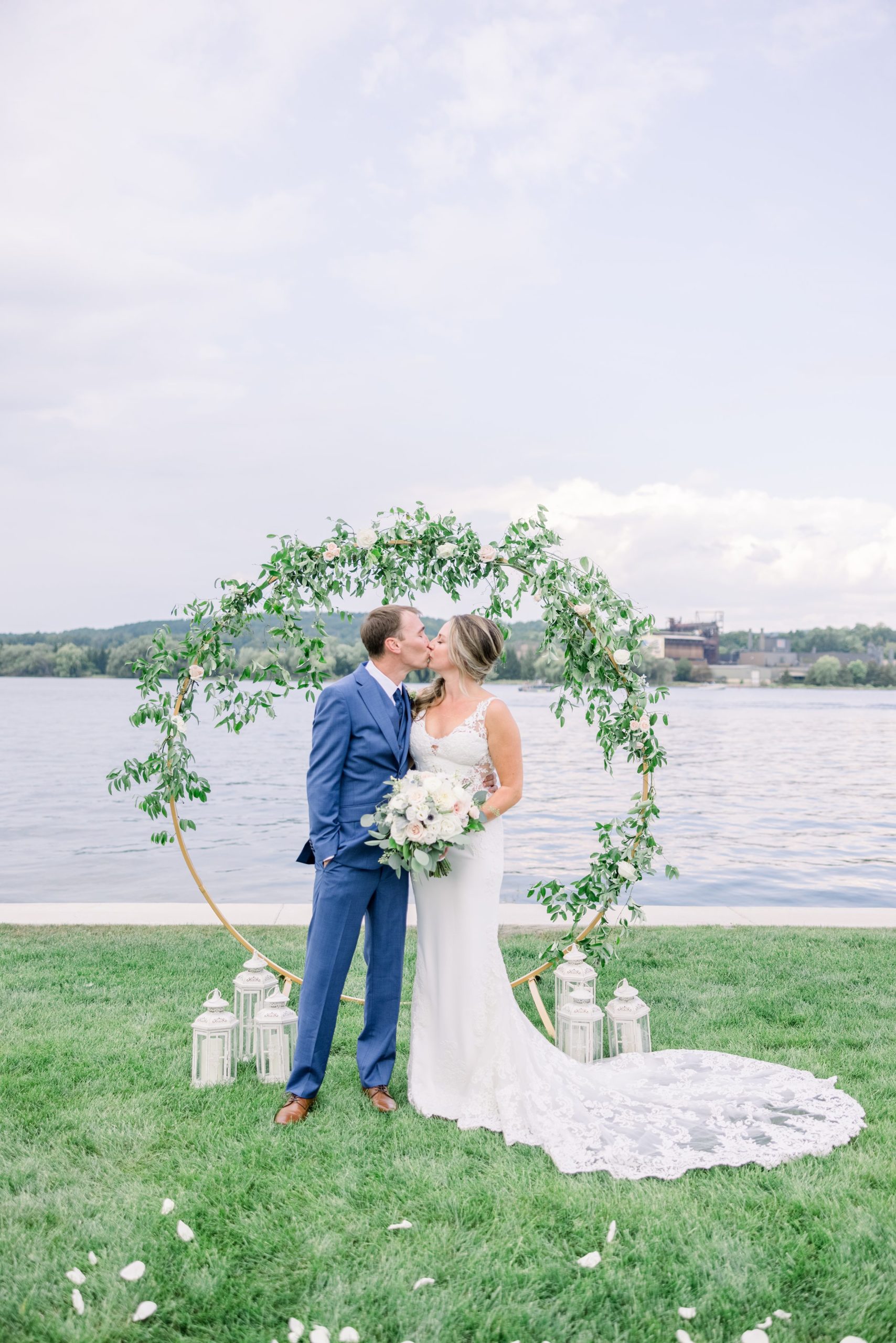 Bride and Groom share a kiss under wedding arch on the shore of Lake Charlevoix in front of The Boathouse