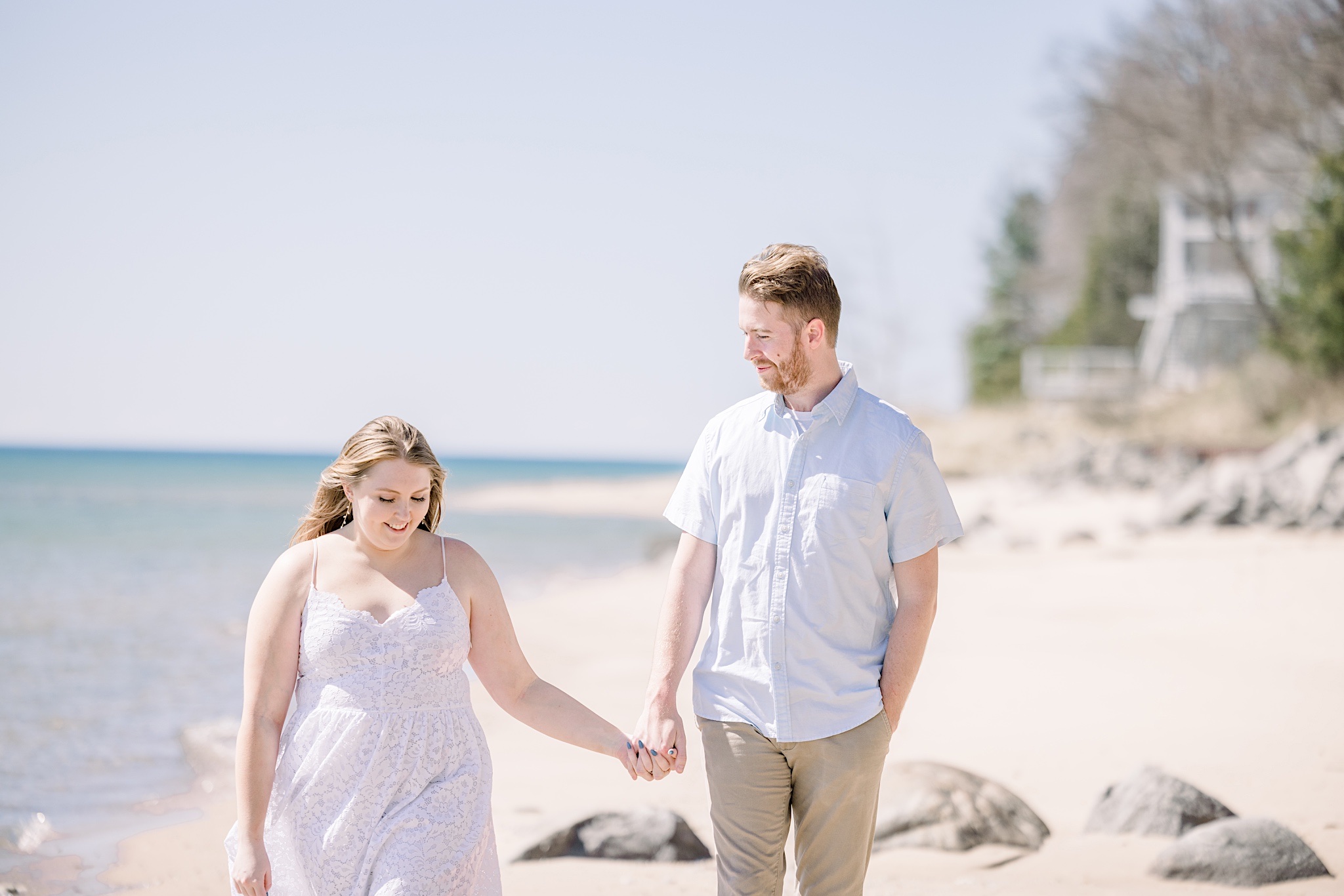 Couple walks along Lake Michigan beach shore during their Harbor Springs engagement session.