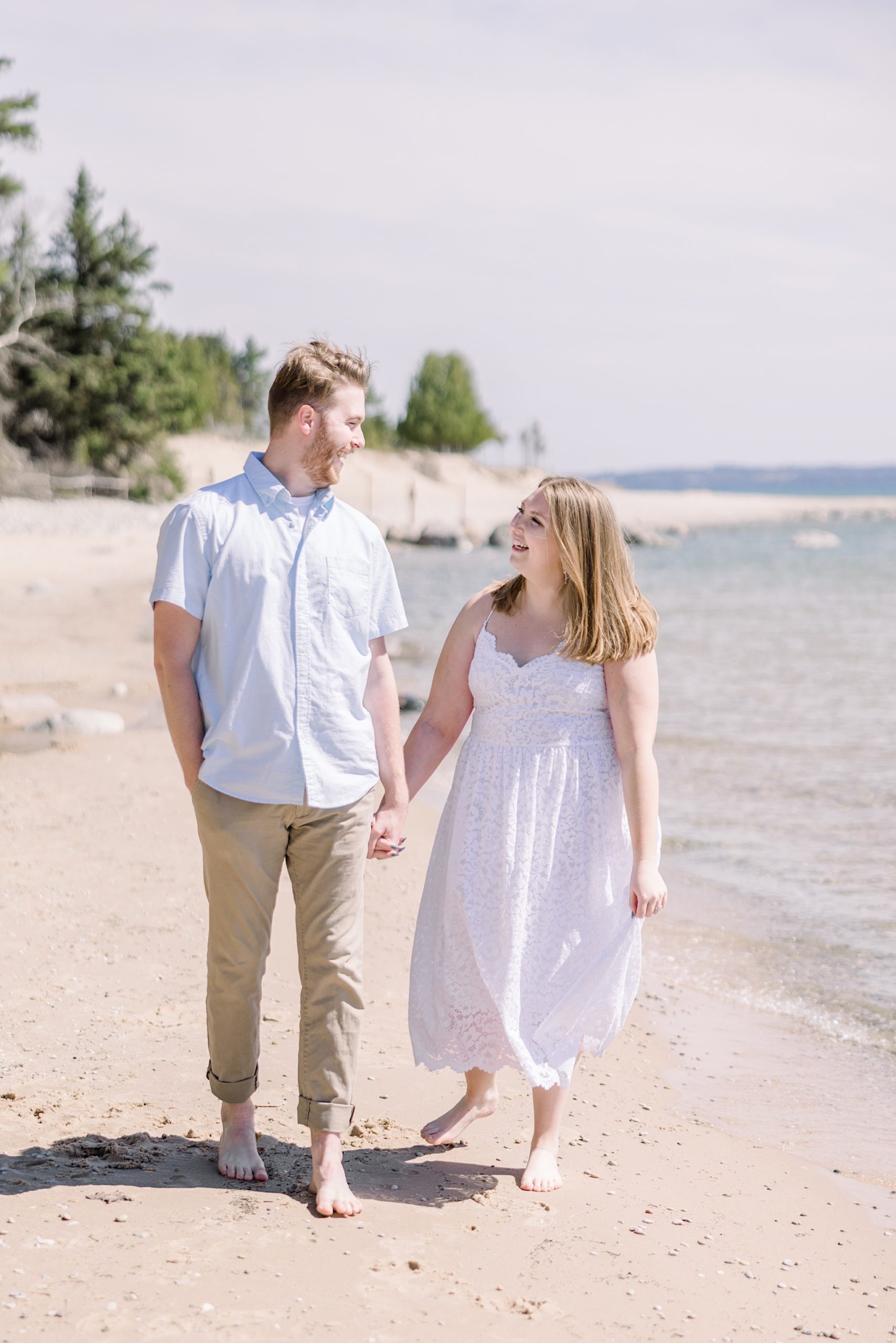 Bride and groom walk along beach together during Harbor Springs Engagement Session.