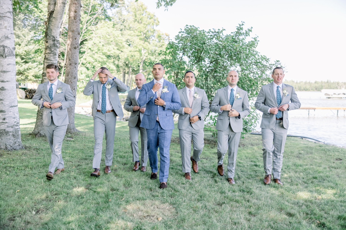 Andres walking with his groomsmen across the lawn of his lake house on his wedding day.