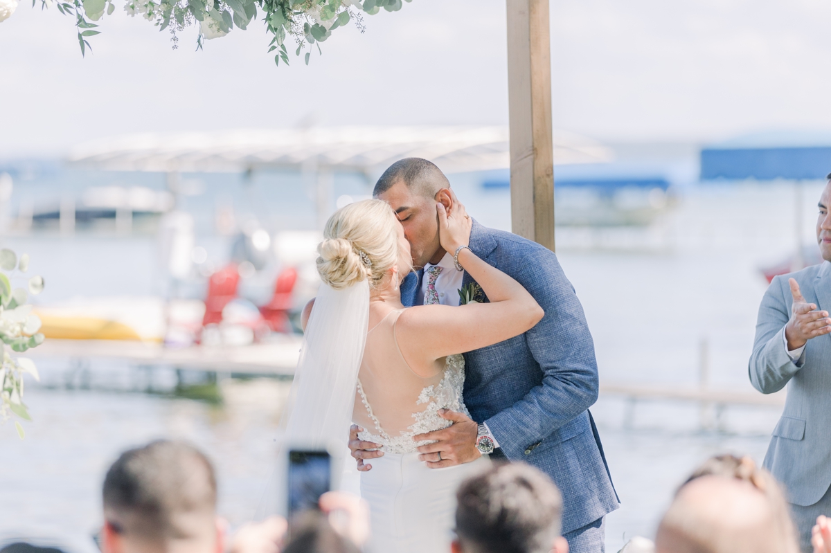Caitlin and Andres kissing for the first time as husband and wife during their Northern Michigan lake house ceremony.